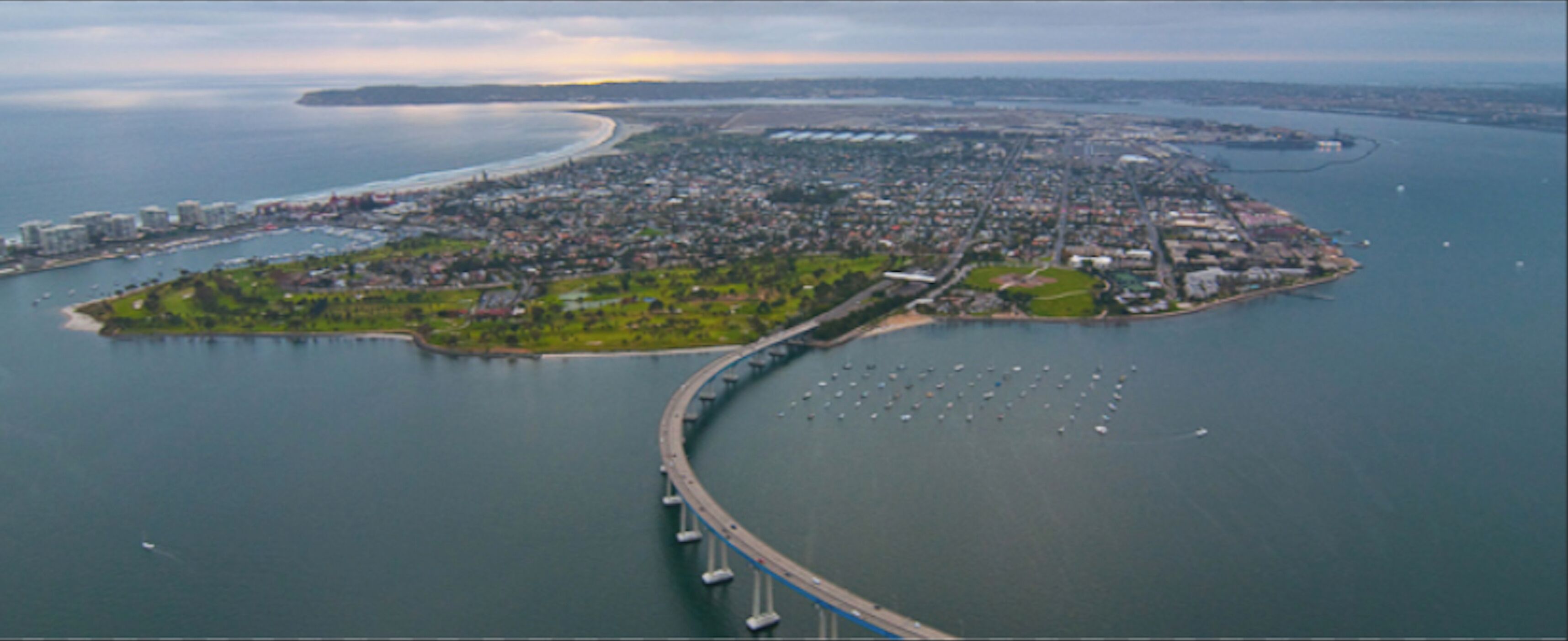 An aerial view of a coastal city with a prominent bridge connecting two land masses.