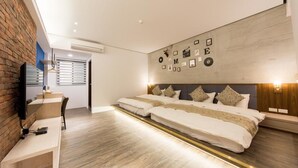 A modern bedroom with a large bed, a desk, and a TV mounted on a brick wall. - Pickup Light (Tainan)