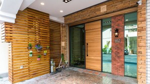 A modern building entrance with a wooden slatted wall, a glass door, and a brick pillar with a sign. - Pickup Light (Tainan)