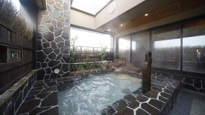 Un espace avec un jacuzzi, des murs en pierre et une terrasse en bois.