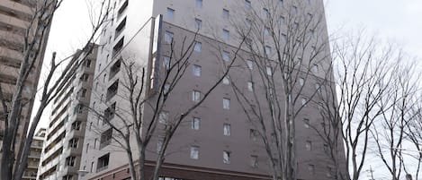 Un edificio de varios pisos con fachada plana, varias ventanas y un letrero que dice "dormy inn".