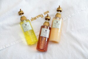 Three bottles of shower products on a white towel.