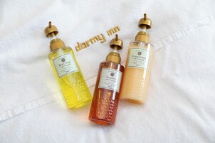 Três frascos de produtos de banho sobre uma toalha branca.