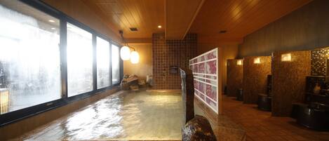 Uma área de spa com hidromassagem, teto de madeira, paredes revestidas de azulejos e janelas amplas.