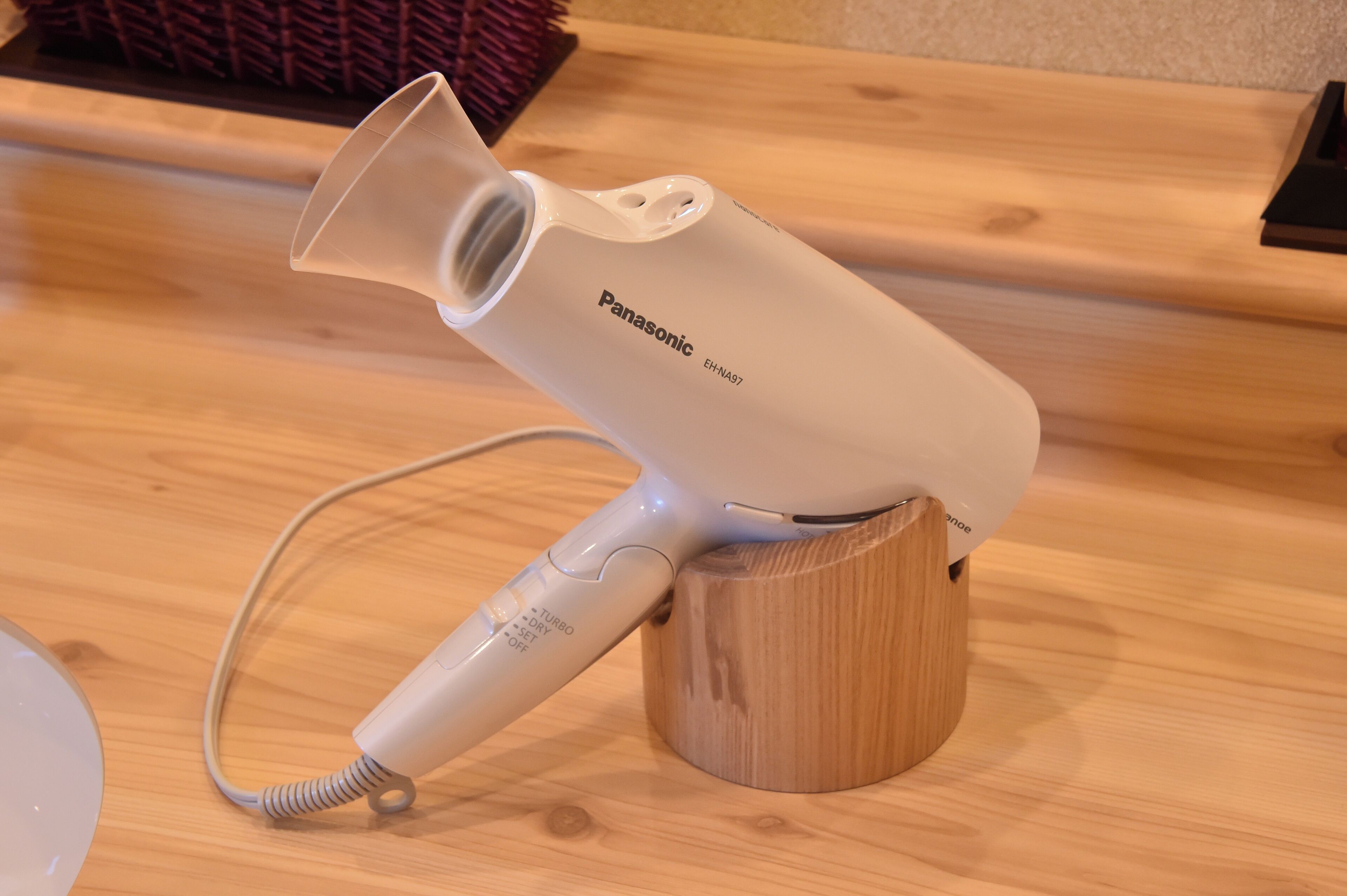 Un secador de pelo Panasonic sobre un soporte de madera.