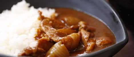 A bowl of white rice and a curry dish with chunks of meat and onions.