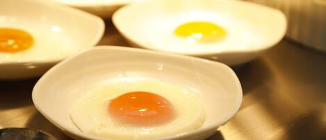 Four small white bowls containing fried eggs.