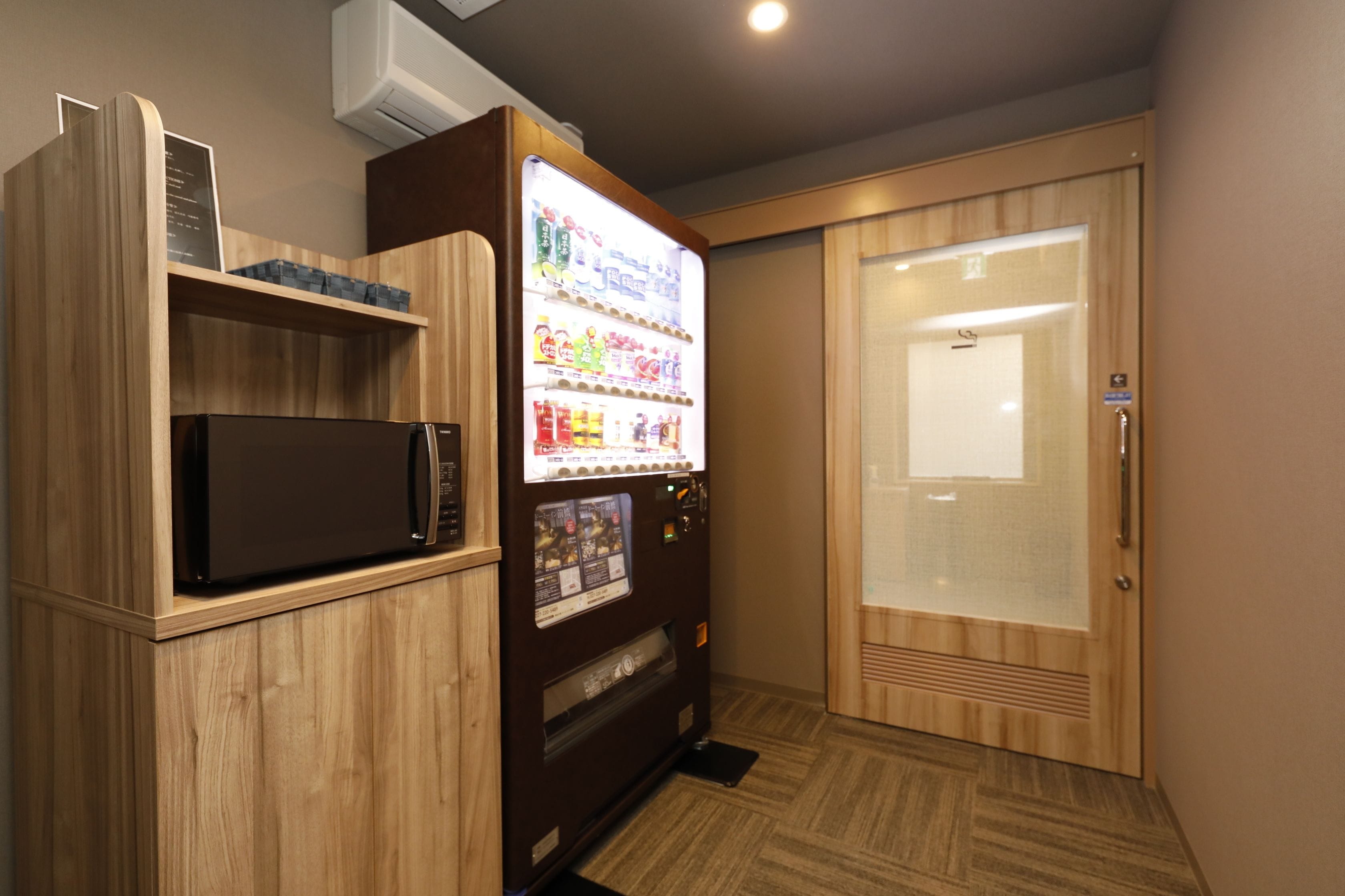 A room with a microwave, vending machine, and a sliding door.