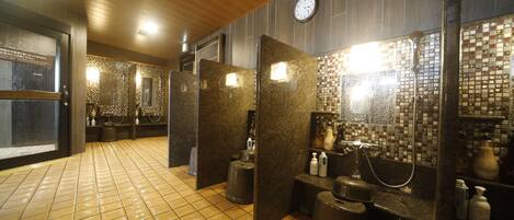 A modern bathroom with tiled floors, granite countertops, and a visible clock on the wall.