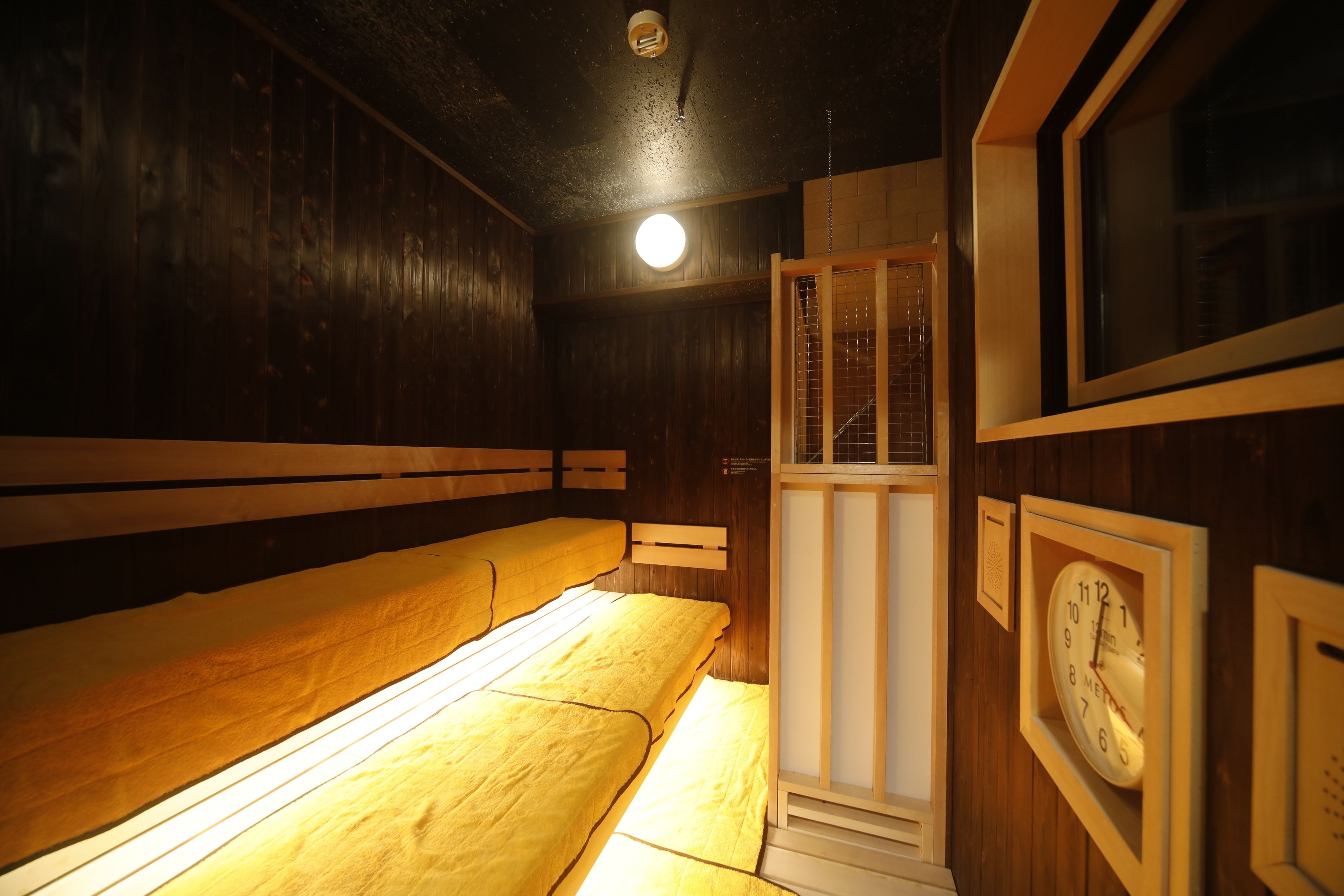A room with wooden walls and benches, a clock, and a door with a window.