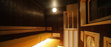 A room with wooden walls and benches, a clock, and a door with a window.