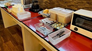 A breakfast bar with various food items, containers, and a coffee maker.