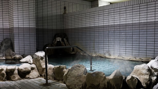 A hot spring area with tiled walls and a pool surrounded by rocks.