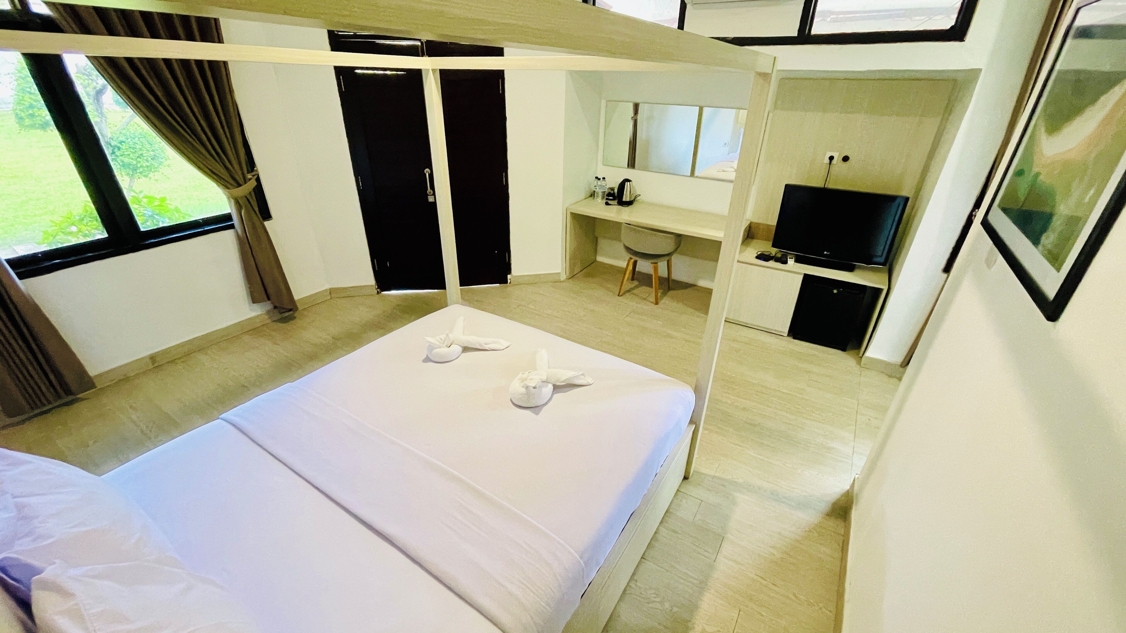 A hotel room with a bed, a desk, a television, and a window with curtains.