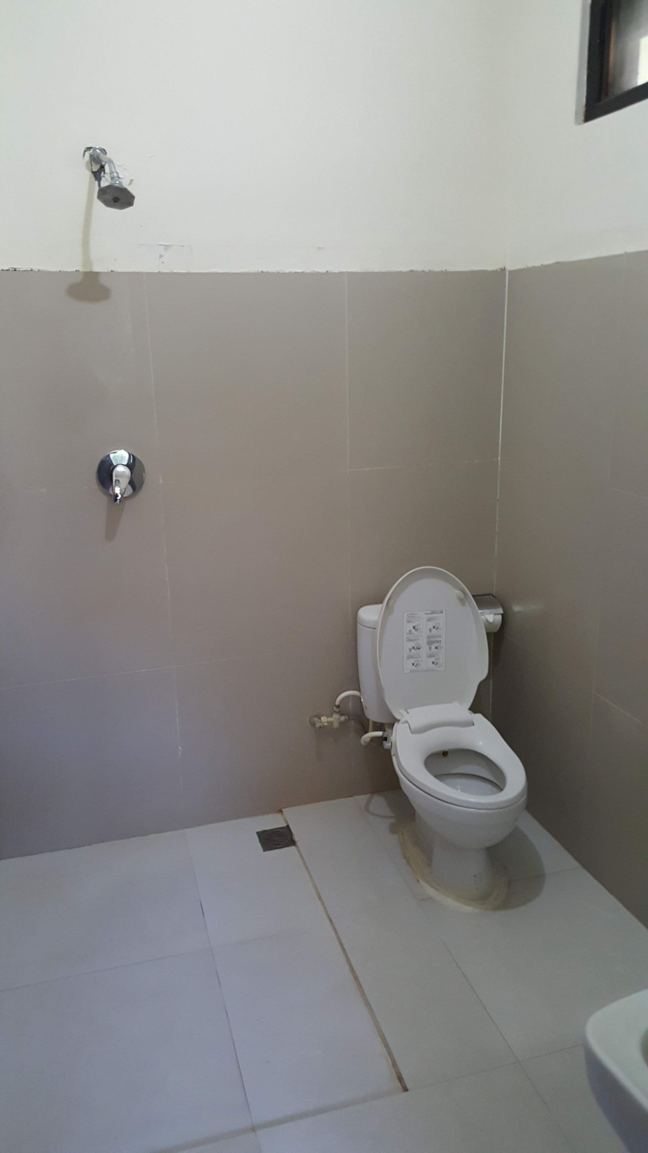 A bathroom with a toilet, a shower, and a sink.
