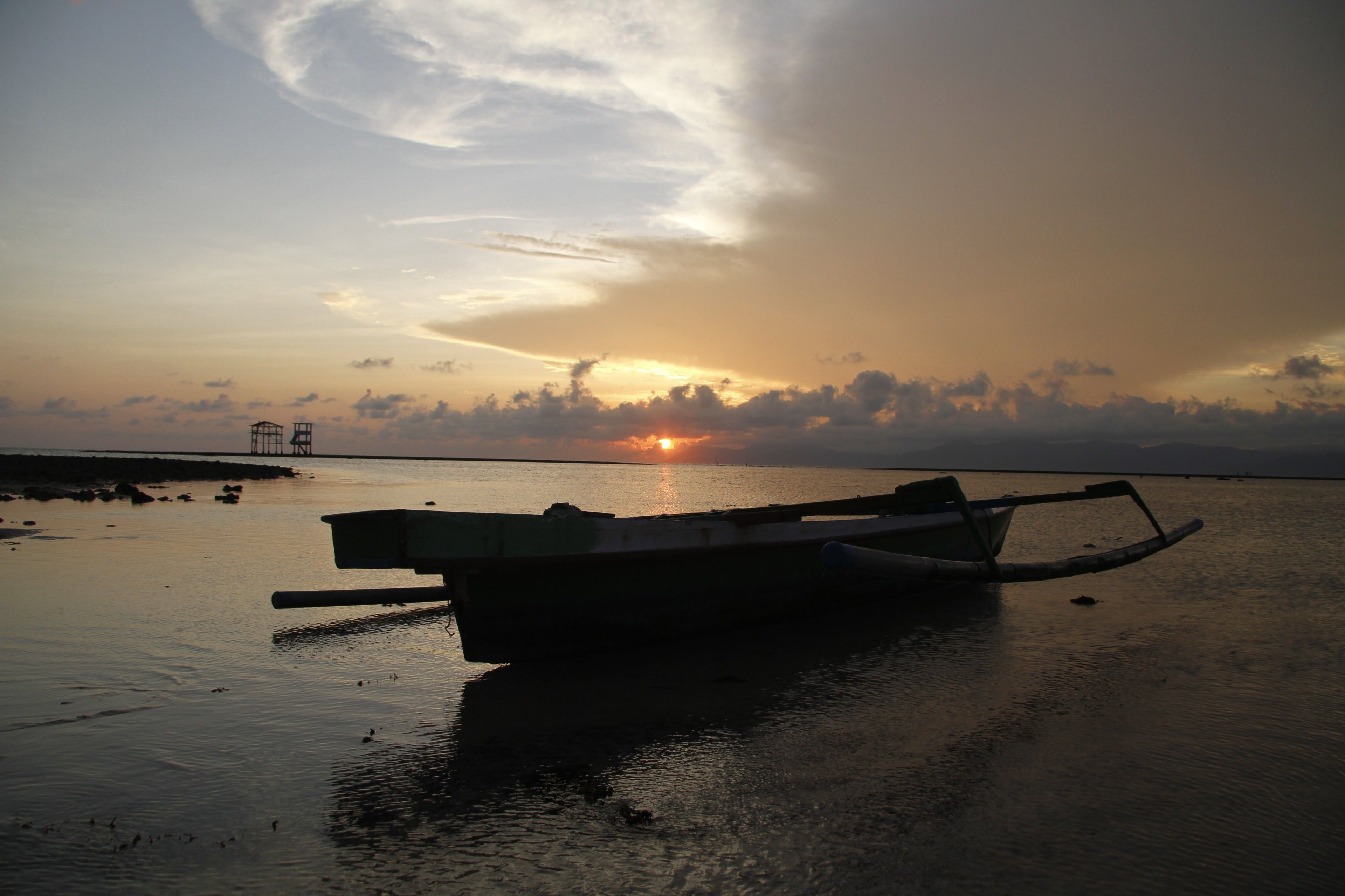 Un bote varado en una superficie acuática tranquila durante el atardecer.
