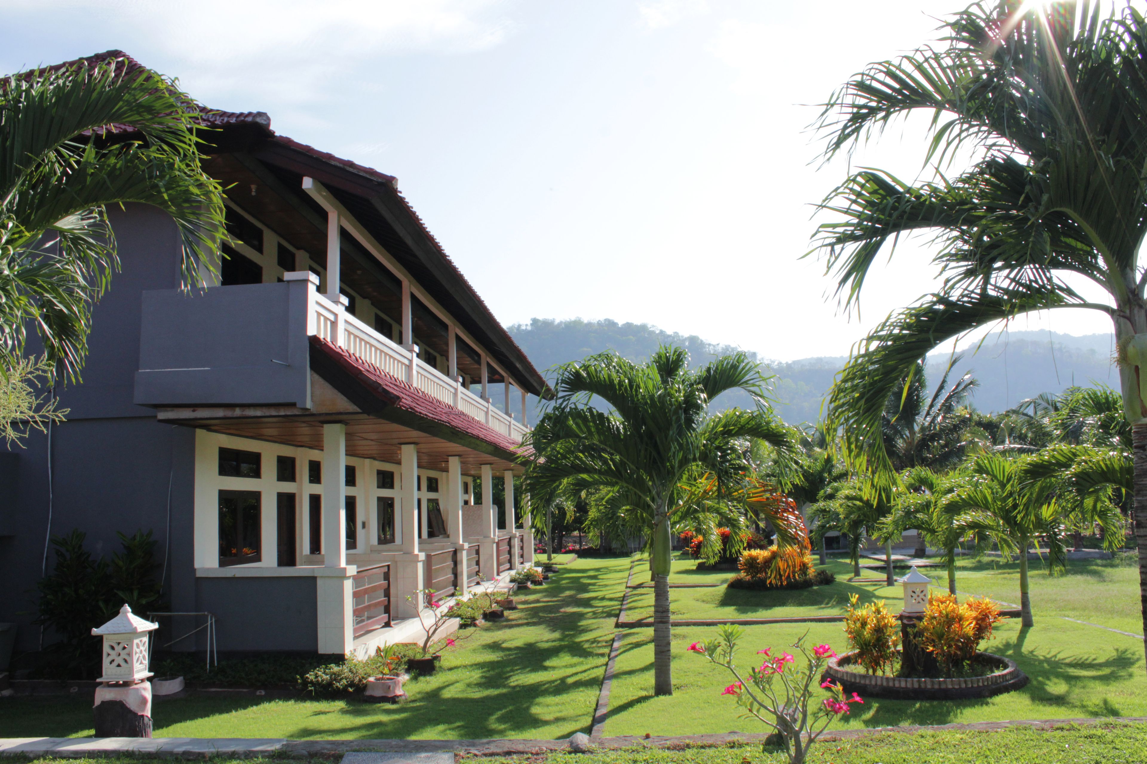A two-story building with a balcony, surrounded by well-maintained lawns and palm trees.
