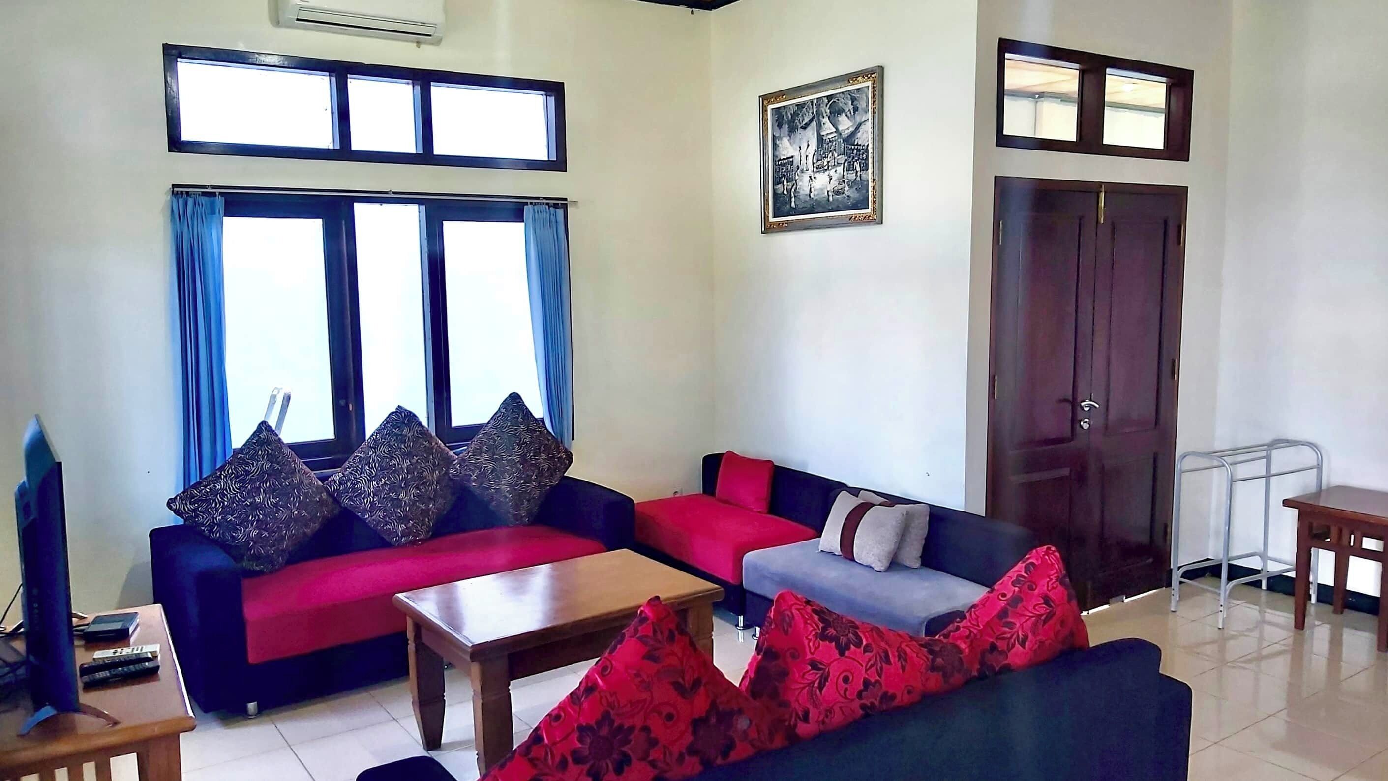 A living room with a sofa set, a coffee table, a TV, and a door.