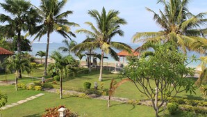 Ein tropischer Garten mit Palmen, einem Pavillon und Blick auf das Meer.