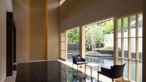 A spacious room with a large window, a black chair, a small table, and a wooden accent wall. - Hoshino Resorts KAI Sengokuhara (Hakone)
