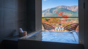 A spa area with a hot tub, two wicker chairs, and a view of mountains. - Hoshino Resorts KAI Sengokuhara (Hakone)