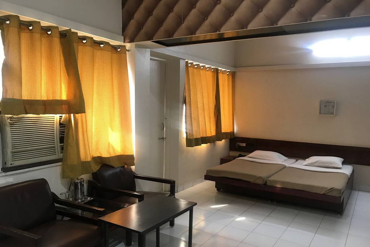 Une chambre d’hôtel avec un lit, un bureau, une chaise et des rideaux.