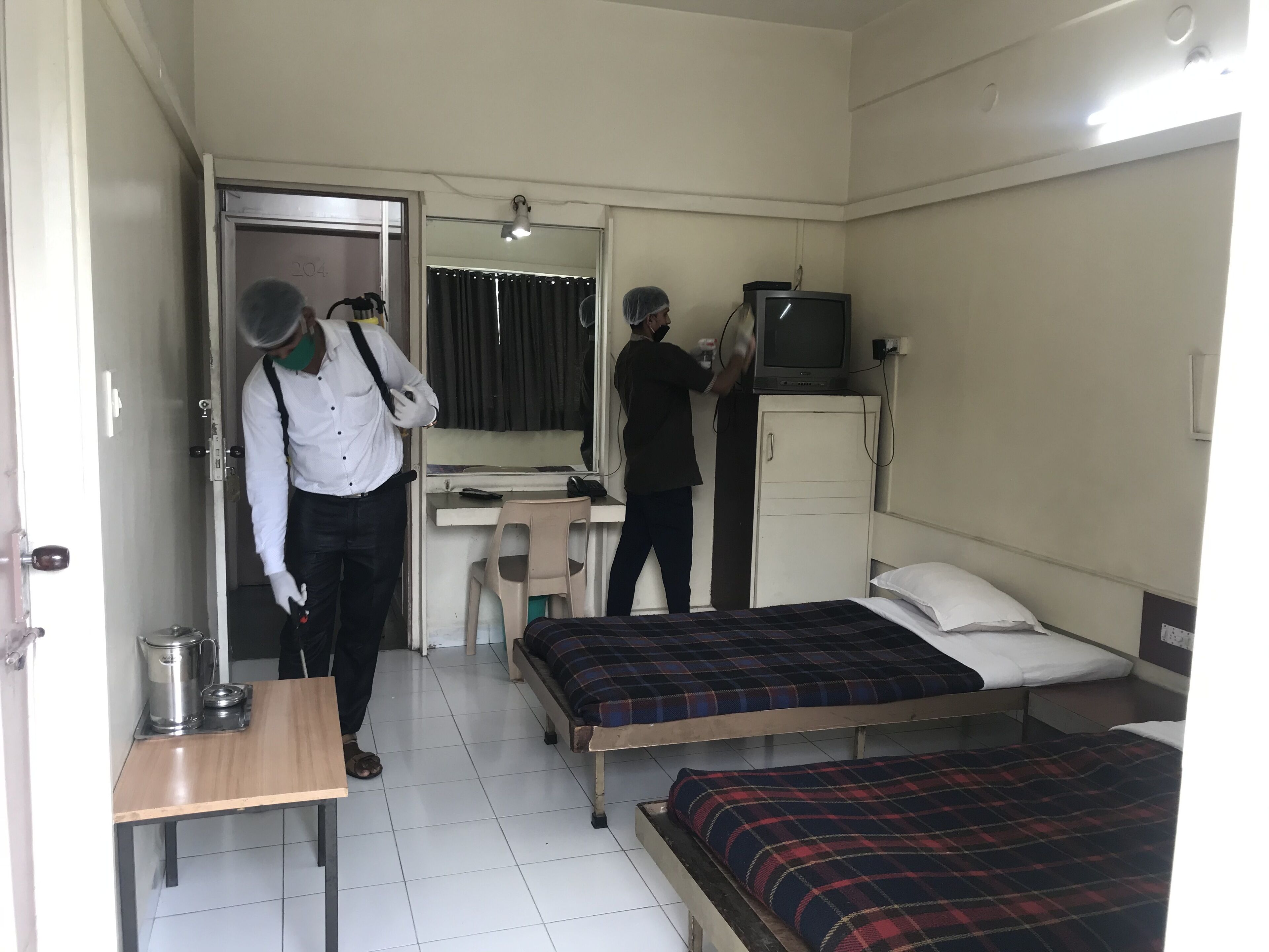 Ein Hotelzimmer mit zwei Betten, einem Schreibtisch, einem Fernseher und einem Schrank.