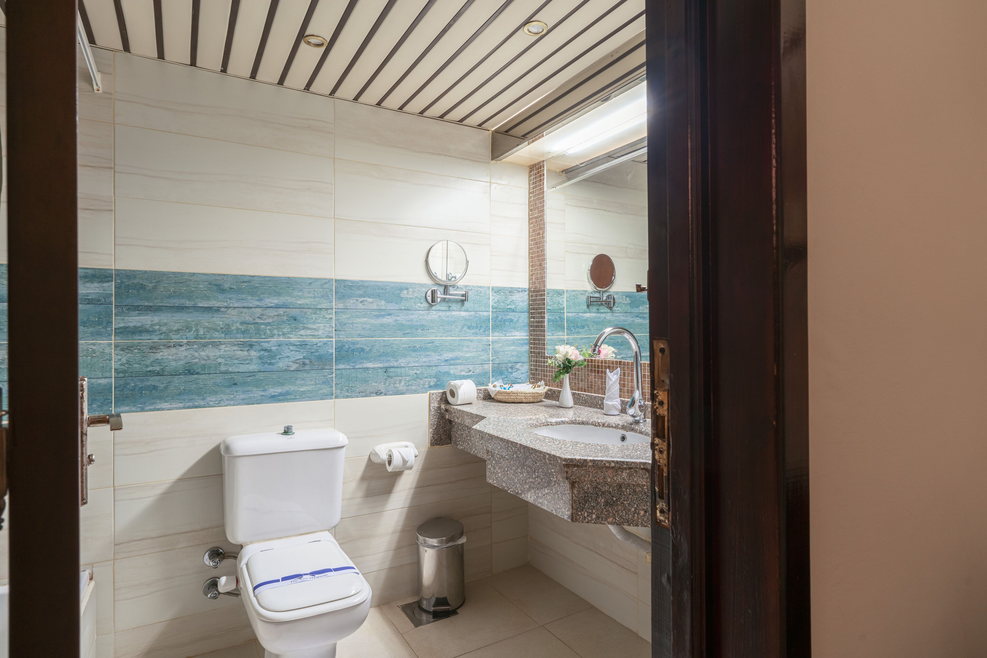 A bathroom with a toilet, sink, and mirror.
