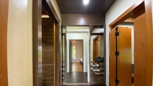A hallway with wooden flooring, a glass door, and a staircase leading to another room.