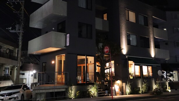 A multi-story building with a ground-level restaurant, large windows, and a visible sign with Japanese characters. - Treeside Hotel & Apartment (Yugawara)