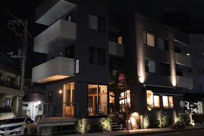 A multi-story building with a ground-level restaurant, large windows, and a visible sign with Japanese characters. - Treeside Hotel & Apartment (Yugawara)