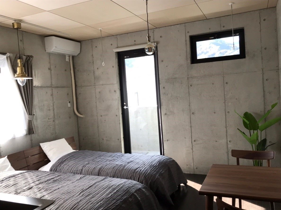 Et værelse med to senge, et bord, en stol, et fjernsyn og en plante.