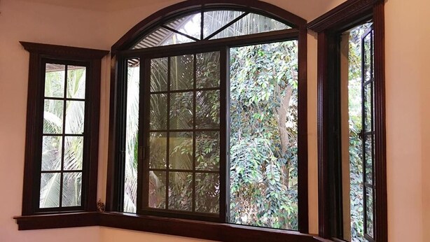 Una habitaci ón con un amplio ventanal de arco, con múltiples vidrios, que ofrece vistas de exuberante follaje exterior.