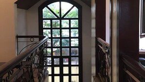 Una escalera con barandilla de metal negro que lleva a una puerta con diseño geométrico.