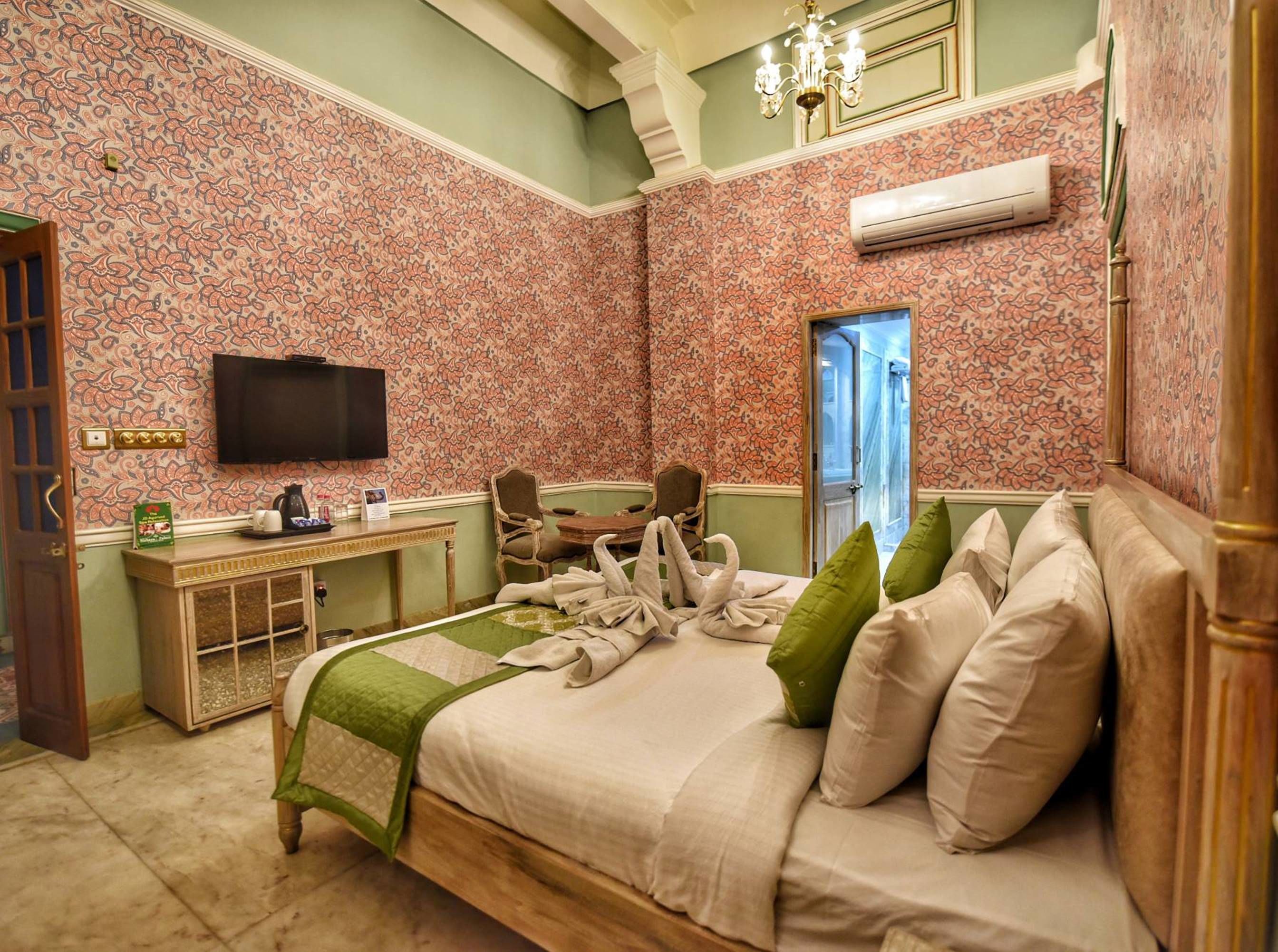 A hotel room with a bed, a desk, a television, and a shower area.
