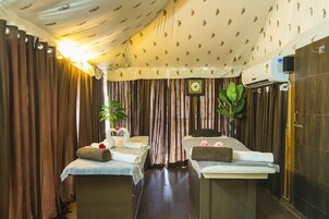 Um quarto com duas mesas de massagem, um relógio e um ar condicionado fixado na parede.