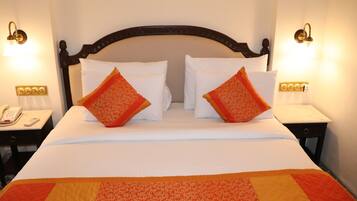 Quarto de hotel com uma cama grande, duas mesas de cabeceira e uma mesinha de apoio com telefone.