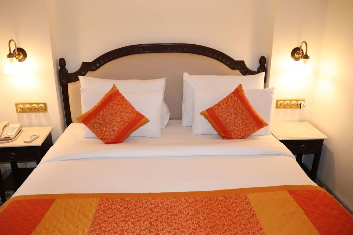 A hotel room with a bed, two bedside tables, a telephone, and wall-mounted lamps.