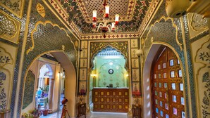 An ornate interior with a patterned floor, a reception desk, and decorative arches. - Nirbana Palace - A Heritage Hotel (Jaipur)