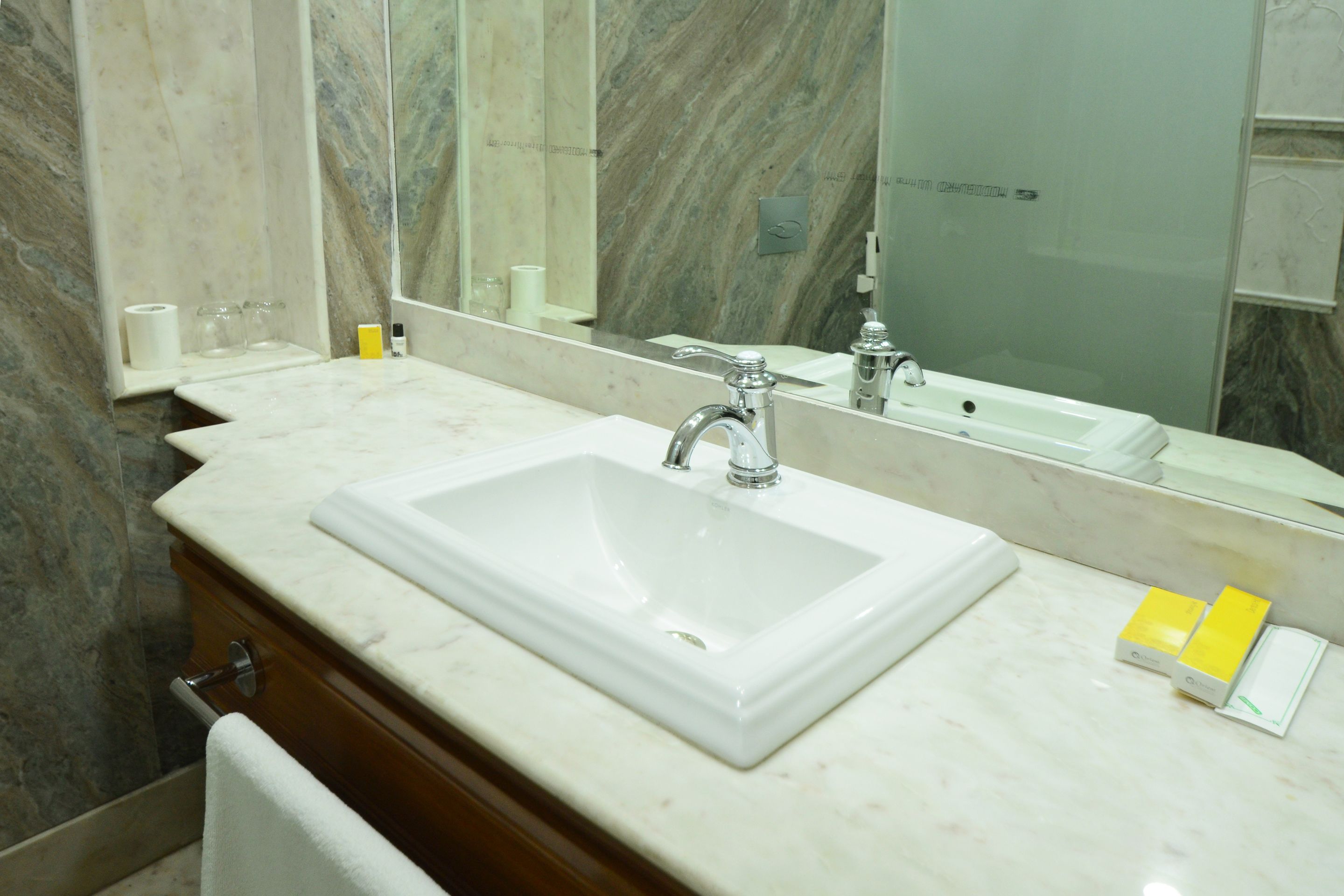 A bathroom with a marble sink, a large mirror, and a glass shower enclosure.