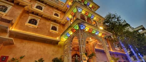 A multi-story building with ornate balconies and a brightly lit entrance.