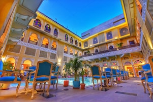 Un patio de hotel con piscina, sillas azules y arquitectura decorada.