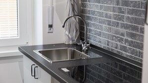 A kitchen with a stainless steel sink, a faucet, and a tiled backsplash. - Rental In Rome Apartment Archimede (Rome)