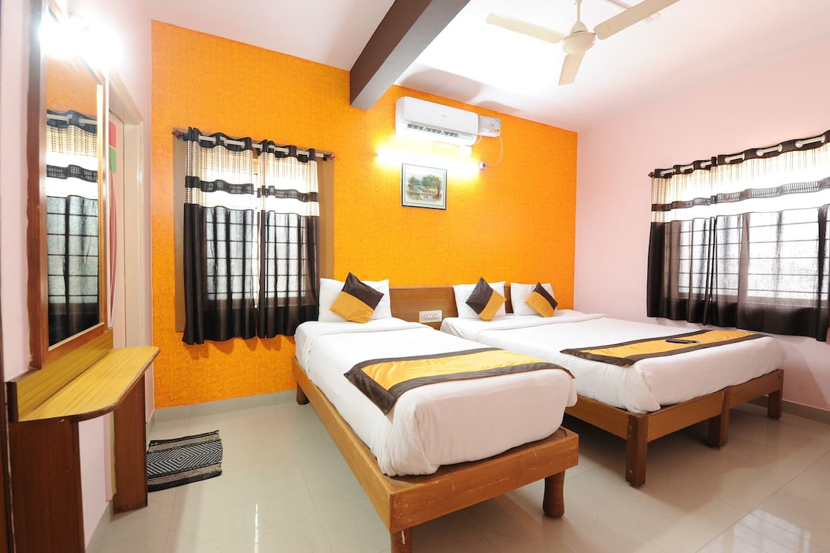 A hotel room with two beds, a ceiling fan, an air conditioner, and a window with curtains.