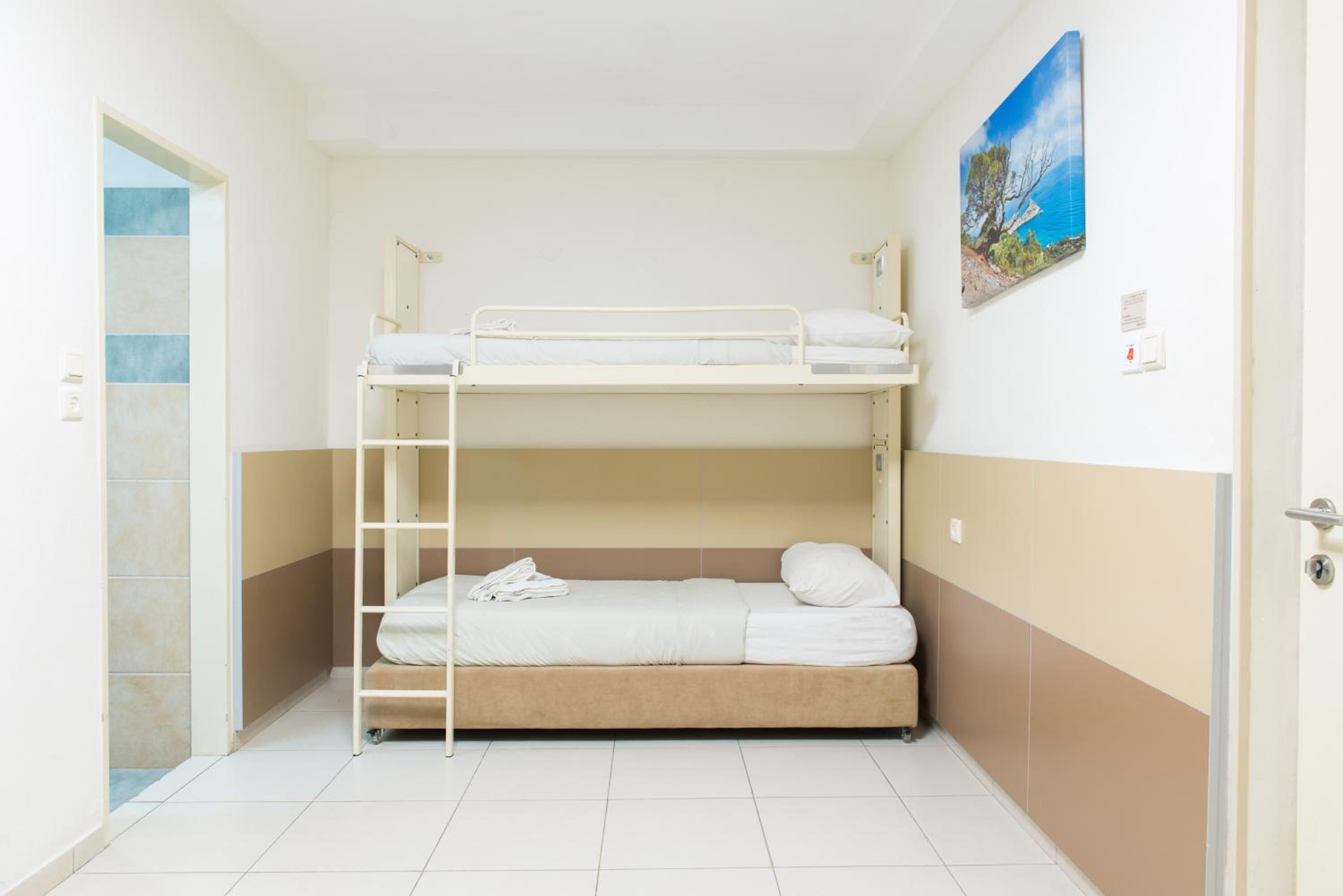 A bunk bed room with a ladder, a painting on the wall, and a door leading to another room.