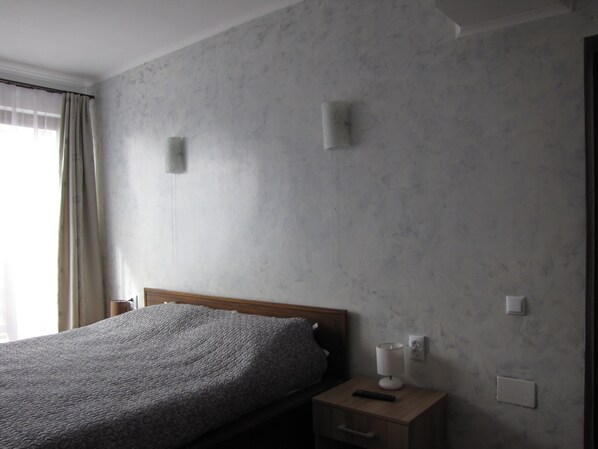 A bedroom with a bed, a nightstand, a lamp, and a wall-mounted light fixture. - Agropensiunea Maris (Feleacu)