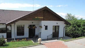 A building with a tiled roof, a sign reading "AGRO PENSIUNE MARIS", and a small entrance with a staircase. - Agropensiunea Maris (Feleacu)