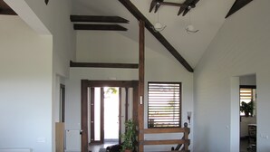 A spacious living area with a high ceiling, wooden beams, a large window with blinds, and a potted plant. - Agropensiunea Maris (Feleacu)