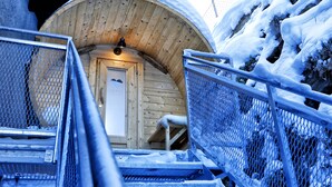 Une cabane en bois, dont l’entrée est recouverte de neige, et un escalier en métal qui y mène.
