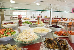 A buffet with various dishes including salads, vegetables, and grilled meats.